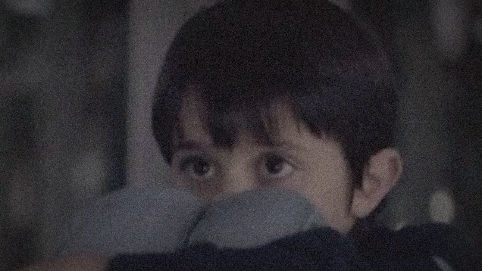 A child alone at the funfair, hugging his knees