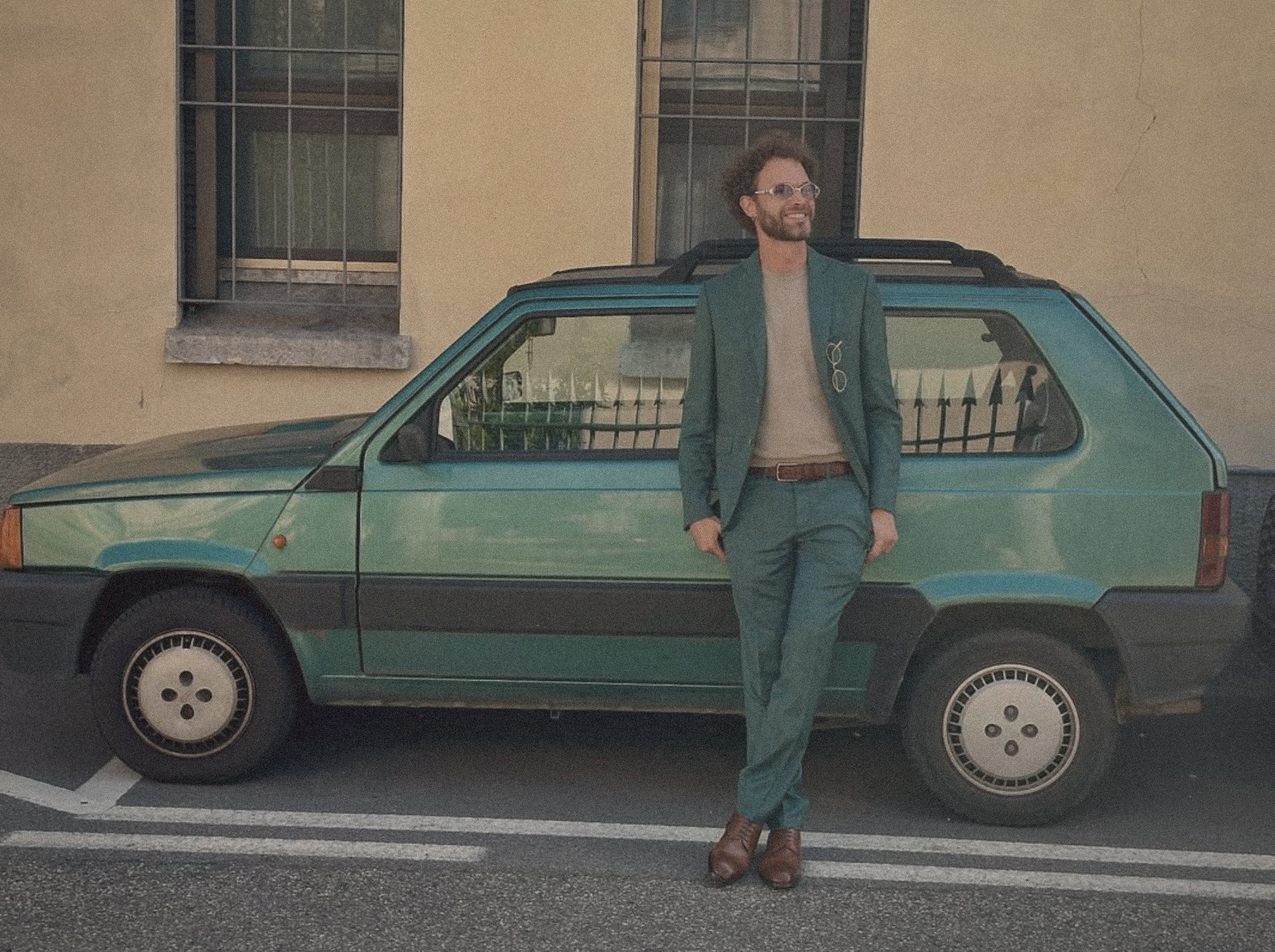 Antonio Serafini leaning on a green Fiat Panda, wearing a green suit, Milan.